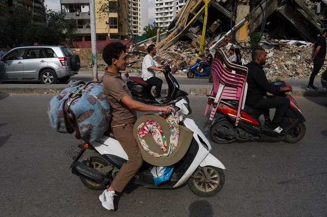 Varias personas regresan a sus hogares en el barrio de Dahieh montadas en motos y cargando sus pertenencias, durante el primer día del alto el fuego recién anunciado entre Israel y el Líbano, el 17 de abril de 2026 en Beirut, Líbano. (Ryan Murphy/Getty Images)