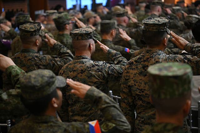 Soldados estadounidenses y filipinos saludan mientras suenan sus himnos nacionales durante la ceremonia de inauguración de las maniobras militares conjuntas anuales «Balikatan» entre Estados Unidos y Filipinas, celebradas en el campamento Aguinaldo de Manila el 21 de abril de 2025. (Foto de Ted ALJIBE / AFP) (Foto de TED ALJIBE/AFP vía Getty Images)