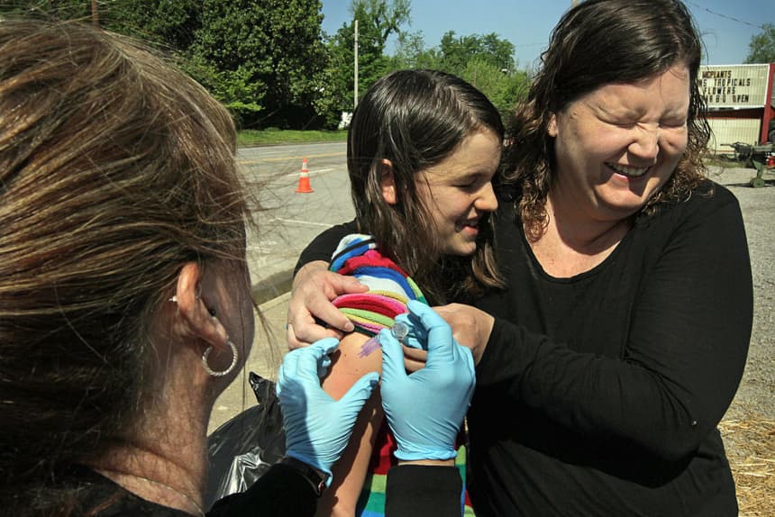 Michele Easter (derecha) sostiene a su hija Caitlyn mientras recibe una vacuna contra el tétanos, en Metropolis, Illinois, el 5 de mayo de 2011. (Scott Olson/Getty Images)