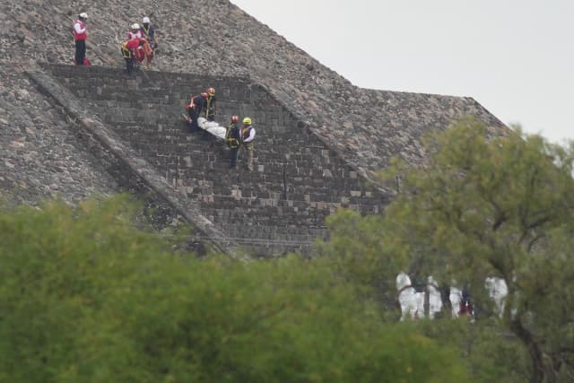 Personal forense traslada el cuerpo de una víctima desde una pirámide después de que, según las autoridades, un hombre armado abriera fuego en Teotihuacán, México, el 20 de abril de 2026. (Eduardo Verdugo/AP Photo).
