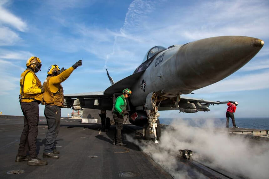 Un marinero estadounidense hace señales a un F/A-18E Super Hornet mientras este se prepara para despegar desde la cubierta de vuelo del portaaviones de la clase Nimitz USS Abraham Lincoln en el mar Arábigo, el 15 de abril de 2026. (Armada de Estados Unidos).