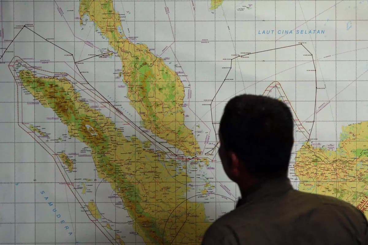Un miembro de la Fuerza Aérea de Indonesia en la base militar de la ciudad de Medan inspecciona un mapa del estrecho de Malaca, un paso marítimo entre Indonesia (a la izquierda del mapa) y Malasia (en la parte superior izquierda del mapa), el 12 de marzo de 2014. (ATAR / AFP vía Getty Images)