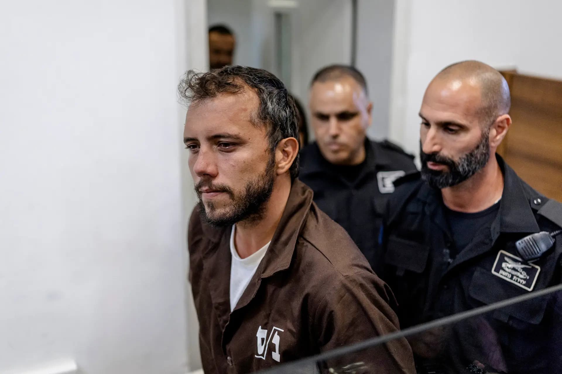 El activista brasileño Thiago Avila es escoltado al interior del tribunal en la ciudad costera israelí de Ashkelon el 5 de mayo de 2026. Se espera que las autoridades israelíes soliciten al tribunal que prorrogue la detención de Avila y del ciudadano español Saif Abu Keshek por seis días, ya que ambos se enfrentan a su segunda vista el 5 de mayo, según ha informado una organización de derechos humanos que los representa. Ambos formaban parte de las decenas de activistas a bordo de una flotilla con destino a Gaza interceptada por las fuerzas israelíes frente a las costas de Grecia en la madrugada del 30 de abril. (Ilia Yefimovich/AFP vía Getty Images).