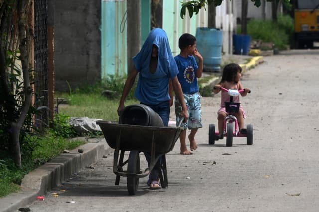 Aquí tienes la traducción:

Niños son vistos en una calle de Chamelecón, en las afueras de San Pedro Sula, Honduras, el 16 de julio de 2022. Chamelecón está bajo el control de pandillas, con una calle que divide los dominios de las bandas Barrio 18 y Mara Salvatrucha (MS-13).(ORLANDO SIERRA/AFP via Getty Images)
