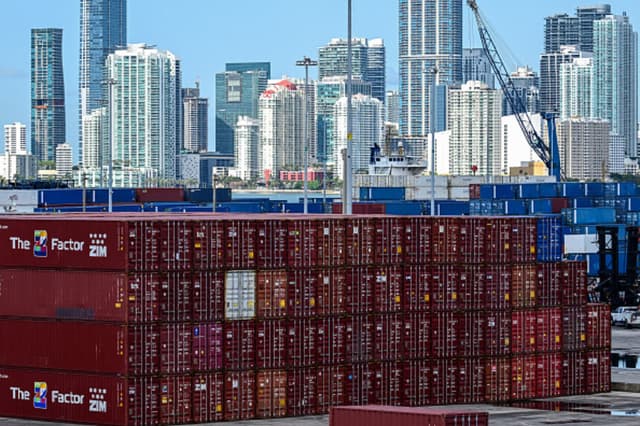 Contenedores apilados en el Puerto de Miami, con panorámica de Miami, Florida, al fondo, el 9 de abril de 2025. China impondrá aranceles del 84 por ciento a las importaciones estadounidenses, frente al 34 por ciento actual, según anunció el miércoles el Ministerio de Finanzas.  (Giorgio VIERA / AFP).