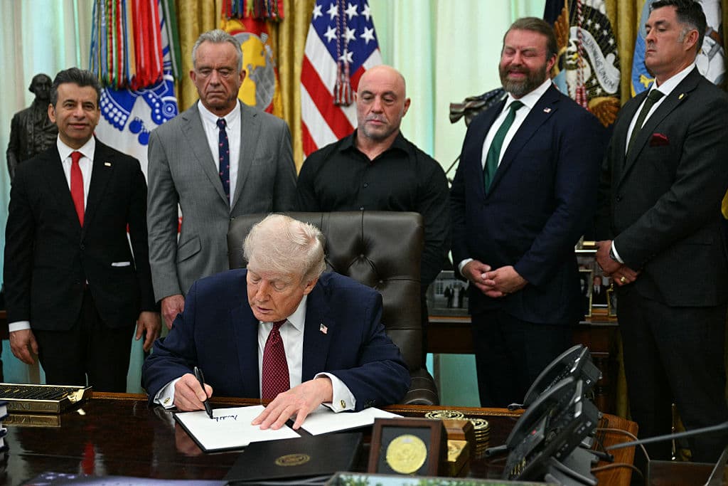 (De izquierda a derecha) El comisionado de la FDA, Marty Makary; el secretario de Salud y Servicios Humanos, Robert F. Kennedy Jr.; el personaje mediático estadounidense Joe Rogan; W. Bryan Hubbard, director ejecutivo de Americans for Ibogaine; y el ex Navy SEAL Marcus Luttrell observan mientras el presidente de EE. UU., Donald Trump, firma una orden ejecutiva en el Despacho Oval de la Casa Blanca en Washington, D.C., el 18 de abril de 2026. La orden ejecutiva tiene como objetivo impulsar la investigación médica federal y los ensayos clínicos en EE. UU. sobre determinadas drogas psicodélicas. (Foto de Jim WATSON / AFP vía Getty Images)