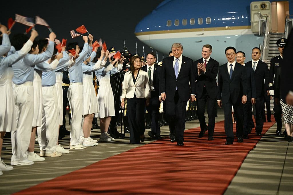 El presidente de EE. UU., Donald Trump (C), y el embajador de EE. UU. en China, David Perdue (centro-D), escoltados por el vicepresidente de China, Han Zheng (D), son recibidos por jóvenes chinos a su llegada al Aeropuerto de Beijing, el 13 de mayo de 2026. (Foto de Brendan SMIALOWSKI / AFP vía Getty Images)