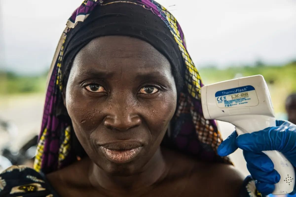 El personal médico toma la temperatura a una mujer que llegó a Uganda desde la República Democrática del Congo a través de la frontera de Busunga, en un centro de detección en el distrito de Bundibugyo, al oeste de Uganda, el 17 de agosto de 2018. (Sumy Sadurni /AFP vía Getty Images)