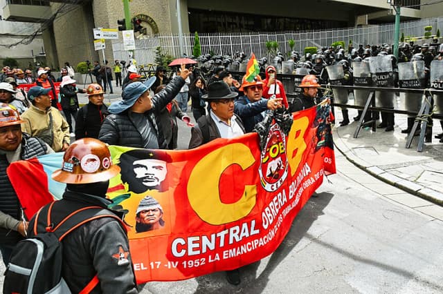 Manifestantes pasan junto a la policía antidisturbios durante una marcha en la que se pedía la renuncia del presidente Rodrigo Paz, en La Paz, el 22 de mayo de 2026. (AIZAR RALDES / AFP vía Getty Images)
