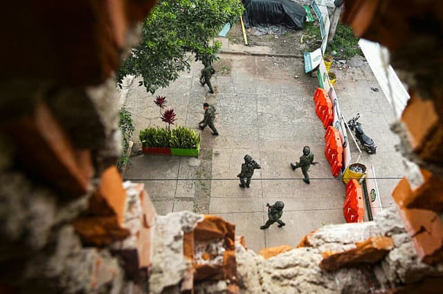 Soldados colombianos patrullan una carretera, vista a través de una pared derruida en un hotel de Suárez, departamento del Cauca, Colombia, el 27 de mayo de 2026. (Joaquín SARMIENTO / AFP vía Getty Images)