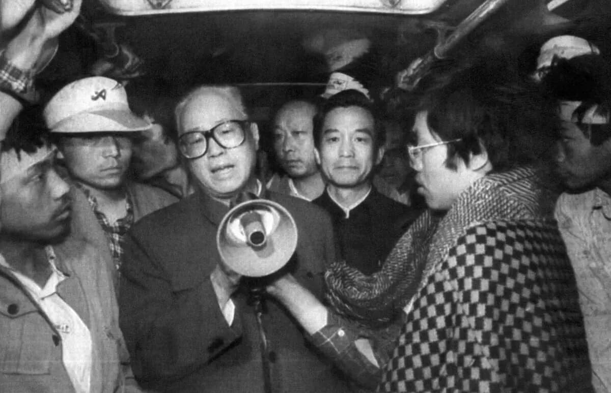 El secretario general del Partido Comunista Chino (PCCh), Zhao Ziyang (C), se dirige a los estudiantes en huelga de hambre a través de un megáfono al amanecer en uno de los autobuses donde se habían refugiado los huelguistas pro-democráticos, en la plaza de Tiananmen de Pekín, el 19 de mayo de 1989. (XINHUA/AFP vía Getty Images).