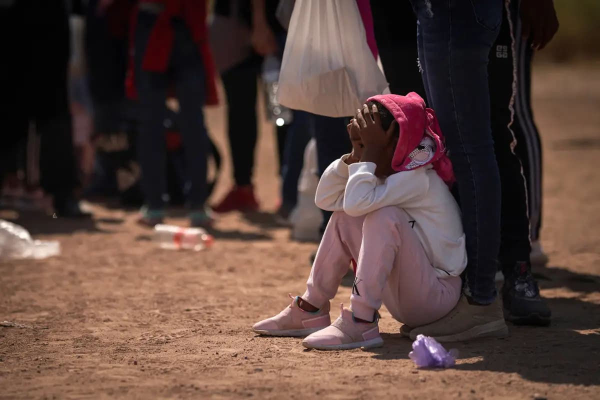 Una niña está sentada en el suelo mientras los inmigrantes ilegales esperan a ser atendidos por los agentes de la Patrulla Fronteriza, en Eagle Pass, Texas, el 9 de octubre de 2022. (Allison Dinner/AFP vía Getty Images).