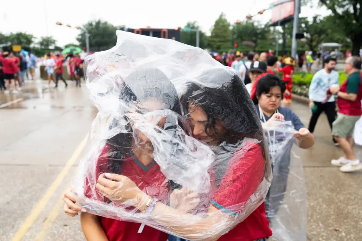 Aficionados de Portugal comparten un chubasquero para protegerse de la lluvia mientras esperan para entrar en el Estadio de Houston antes de un partido de la Copa del Mundo de la FIFA entre Portugal y el Congo en Houston, Texas, el 17 de junio de 2026. (Jason Fochtman/Houston Chronicle vía AP)