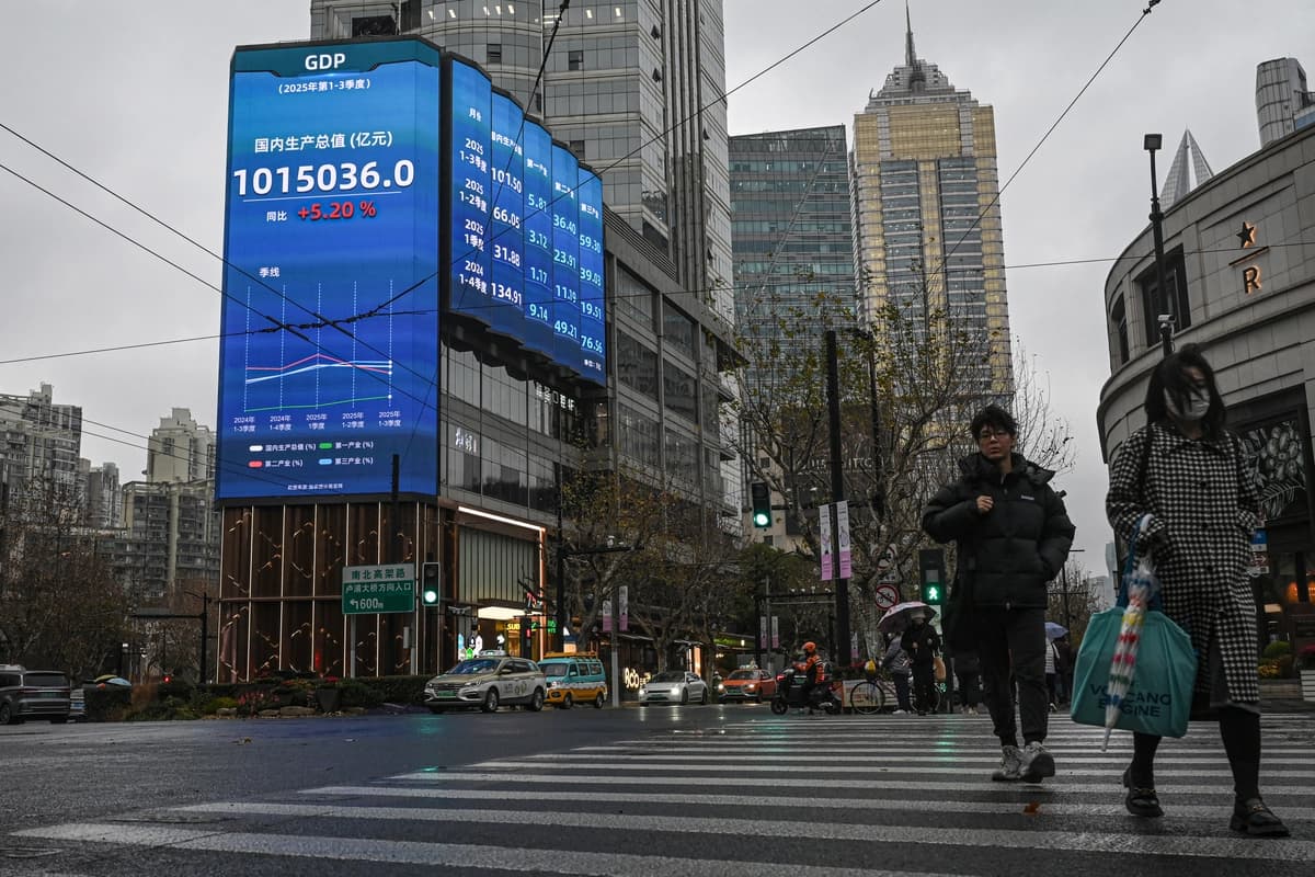 Varias personas pasan junto a una pantalla que muestra cifras del producto interior bruto en una calle de Shanghái el 19 de enero de 2026. (Jade Gao / AFP vía Getty Images). 
