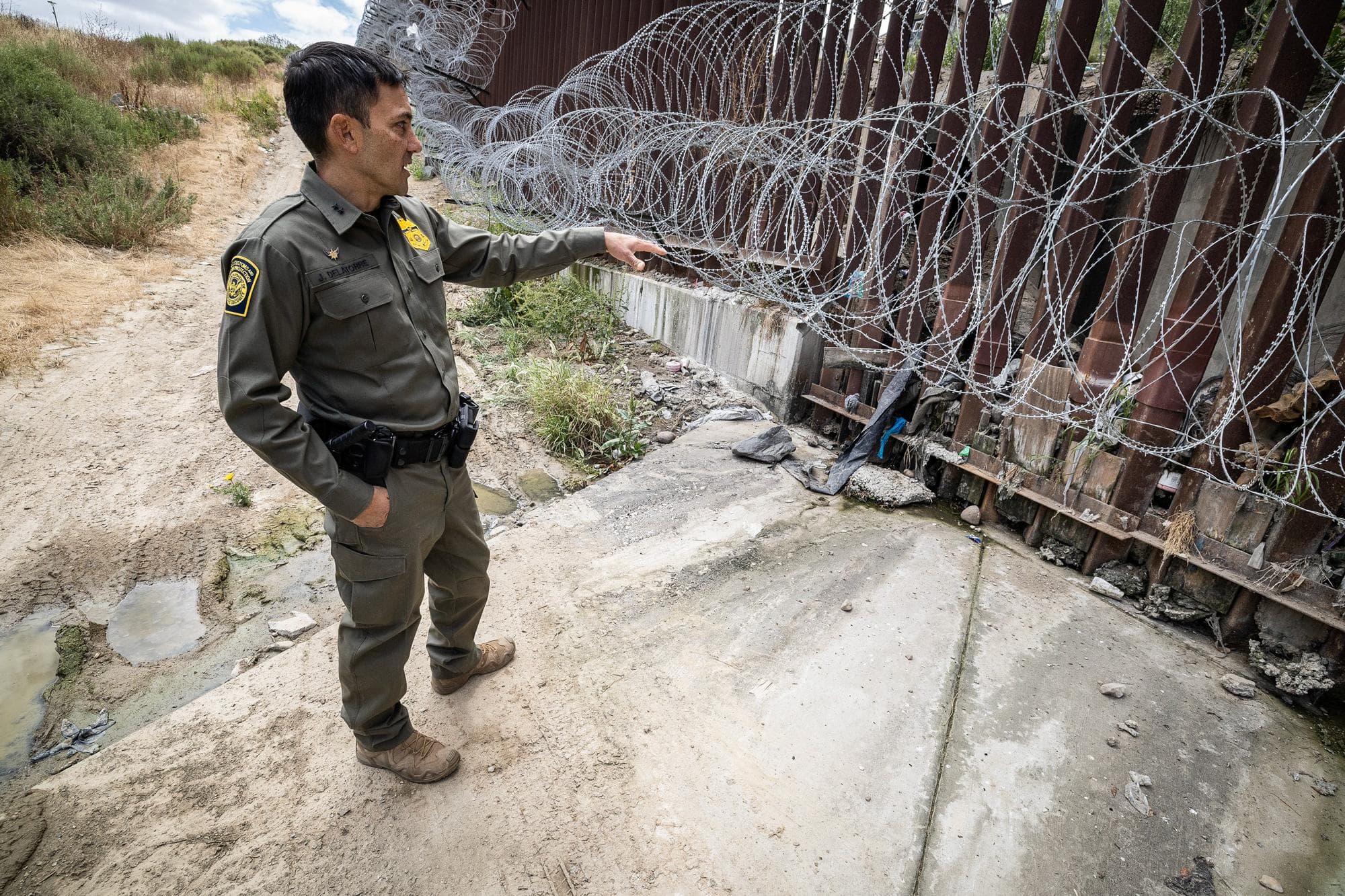 El agente jefe de patrulla Justin M. De La Torre, del Sector de San Diego de la Patrulla Fronteriza de EE. UU., inspecciona el muro fronterizo sur a las afueras de San Diego el 27 de mayo de 2026. De La Torre destacó la mayor coordinación con las fuerzas del orden mexicanas para interceptar a los delincuentes antes de que lleguen a la frontera de EE. UU. (John Fredricks/The Epoch Times).