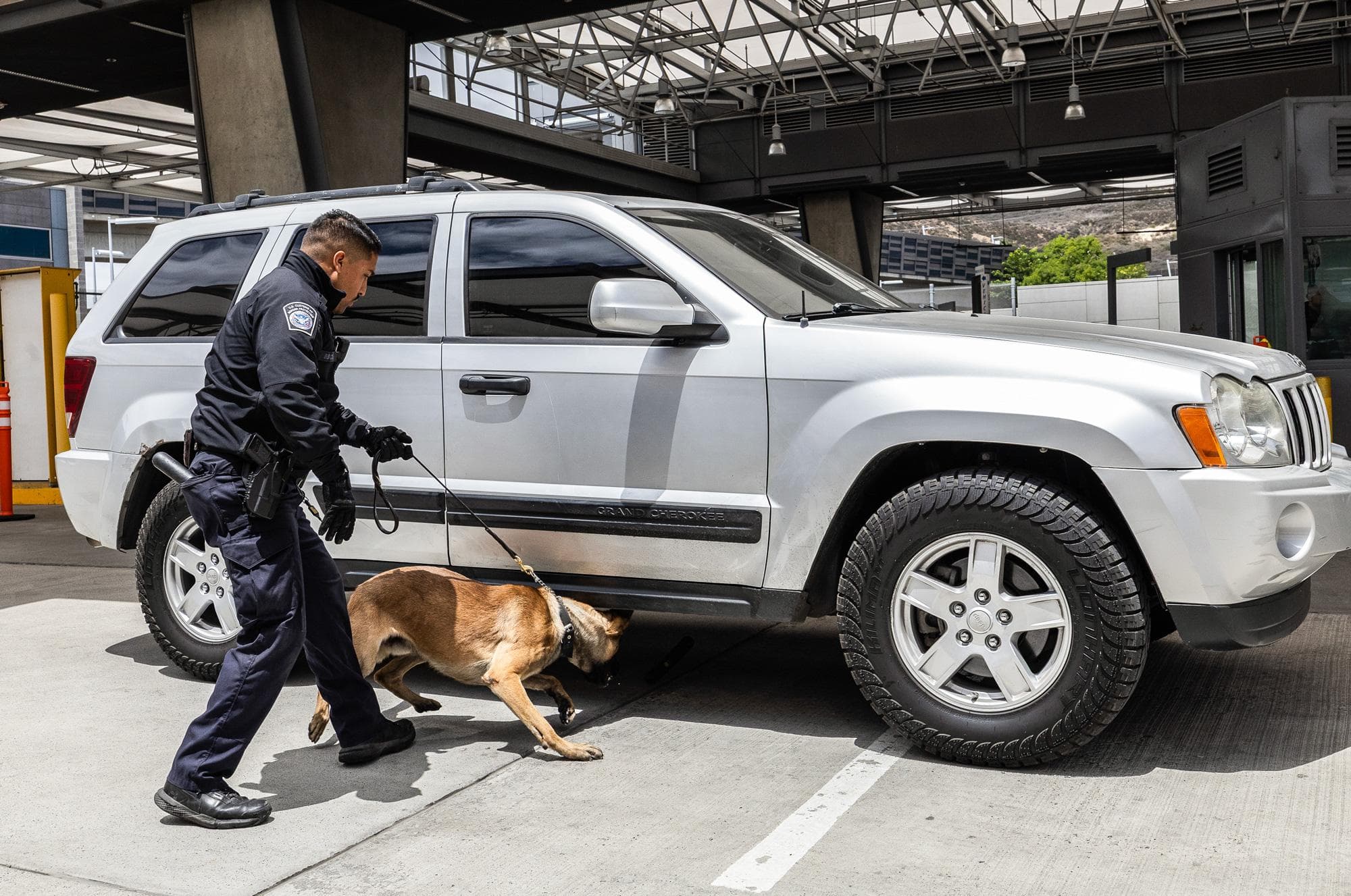 Una unidad canina de la Oficina de Aduanas y Protección Fronteriza de EE. UU. inspecciona un vehículo en el puesto fronterizo entre EE. UU. y México, a las afueras de San Diego, el 26 de mayo de 2026. Antes de llegar al agente encargado de la inspección, los conductores y los vehículos son sometidos a un control por parte de equipos caninos itinerantes y detectores de densidad. (John Fredricks/The Epoch Times).