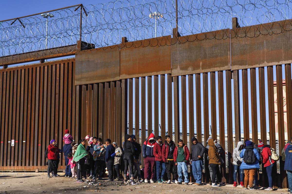 Inmigrantes ilegales de Nicaragua, Ecuador y otros países esperan junto a una puerta del muro fronterizo a ser recogidos por la Patrulla Fronteriza de EE. UU. en El Paso, Texas, el 4 de enero de 2023. (Paul Ratje/Reuters)