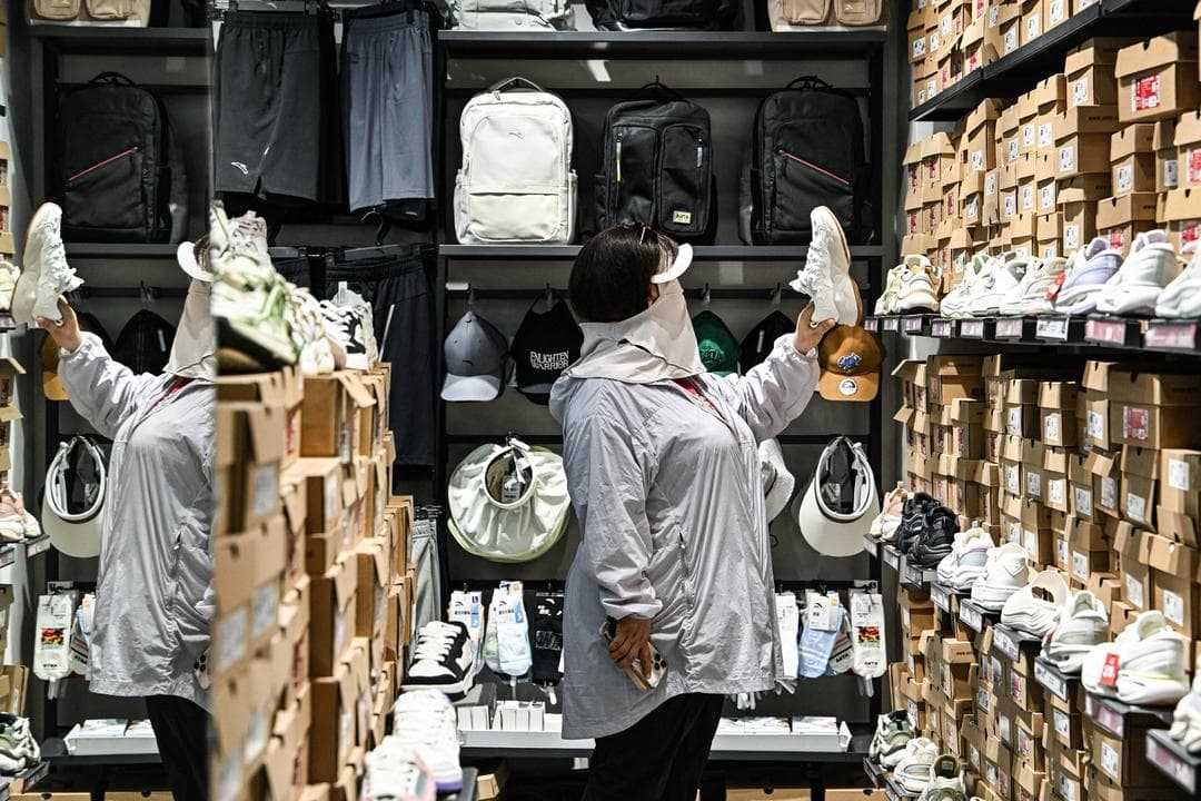 Una mujer revisa unos zapatos en una tienda de Anta, perteneciente a la importante empresa china de ropa deportiva Anta Sports Products Limited, en Beijing el 5 de junio de 2025. Las marcas nacionales ocupaban el 76 % del mercado de consumo de China en 2024, frente al 66 % de 2012, según una encuesta. (Adek Berry / AFP vía Getty Images)