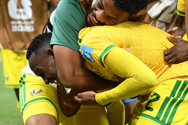El delantero sudafricano Thapelo Maseko, número 12 del ranking, es abrazado por sus compañeros tras marcar el primer gol de su equipo durante el partido de fútbol del Grupo A de la Copa Mundial 2026 entre Sudáfrica y Corea del Sur, disputado en el Estadio Monterrey de Guadalupe, México, el 24 de junio de 2026. (YURI CORTEZ / AFP vía Getty Images).