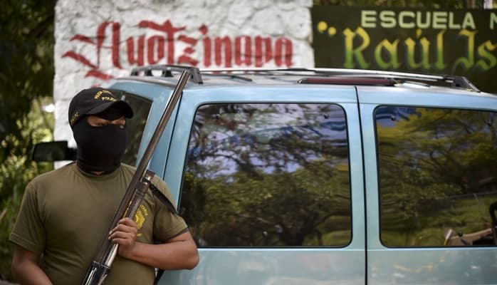 <em>Un miembro de la guardia de autodefensa vigila la entrada principal de la Escuela Normal Rural Raúl Isidro Burgos, donde estudiaban los 43 alumnos desaparecidos, el 15 de octubre de 2014 en Ayotzinapa, Guerrero, México. (Yuri Cortez/AFP vía Getty Images)</em>