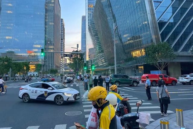 La foto muestra a la policía en máxima alerta tras el impacto de una pequeña aeronave en la Torre CITIC el 26 de junio de 2026. (Peter Catterall/AFP).