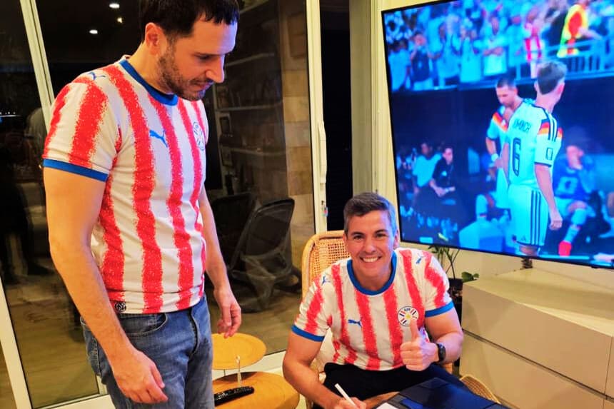 Fotografía difundida en la cuenta en X @SantiPenap del presidente de Paraguay, Santiago Peña (d), firmando el decreto N.º 6280 que declara feriado nacional el martes 30 de junio para celebrar la clasificación de la selección a los octavos de final del Mundial de la FIFA 2026 tras vencer a Alemania. EFE/ @SantiPenap 