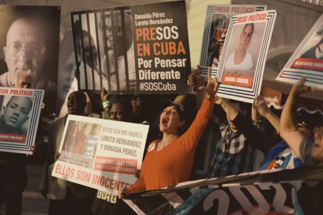 Varias personas sostienen fotografías de presos políticos recluidos en cárceles cubanas, el 18 de marzo de 2024, en Miami, Florida. (Joe Raedle/Getty Images)