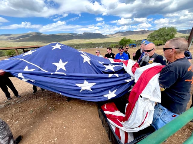 Voluntarios llevan una bandera estadounidense de 30 por 60 pies hasta sus dos mástiles gemelos durante una ceremonia del Día de la Bandera en Mayer, Arizona, el 14 de junio de 2026. (Allan Stein/The Epoch Times)
