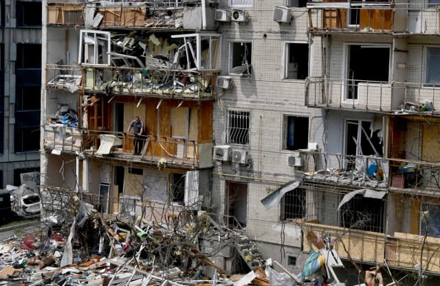 Un residente local se encuentra en el balcón de su departamento en un edificio residencial dañado por un ataque aéreo ruso contra la capital ucraniana, Kiev, el 3 de julio de 2026. Rusia lanzó su mayor ataque aéreo contra Kiev en la madrugada del 2 de julio, lo que causó la muerte de al menos 50 personas, según el alcalde de la ciudad. (Sergei Supinsky / AFP vía Getty Images)