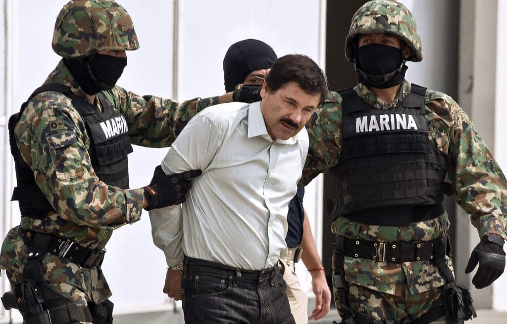 <em>El narcotraficante mexicano Joaquín Guzmán Loera, alias "el Chapo" Guzmán (centro), es escoltado por infantes de Marina durante su presentación ante la prensa en Ciudad de México, el 22 de febrero de 2014. El líder del Cártel de Sinaloa, entonces el hombre más buscado por las agencias antidrogas de Estados Unidos y México, había sido detenido esa misma madrugada por marinos mexicanos en un complejo turístico de Mazatlán, en el norte de México. (Ronaldo Schemidt/AFP vía Getty Images)</em>