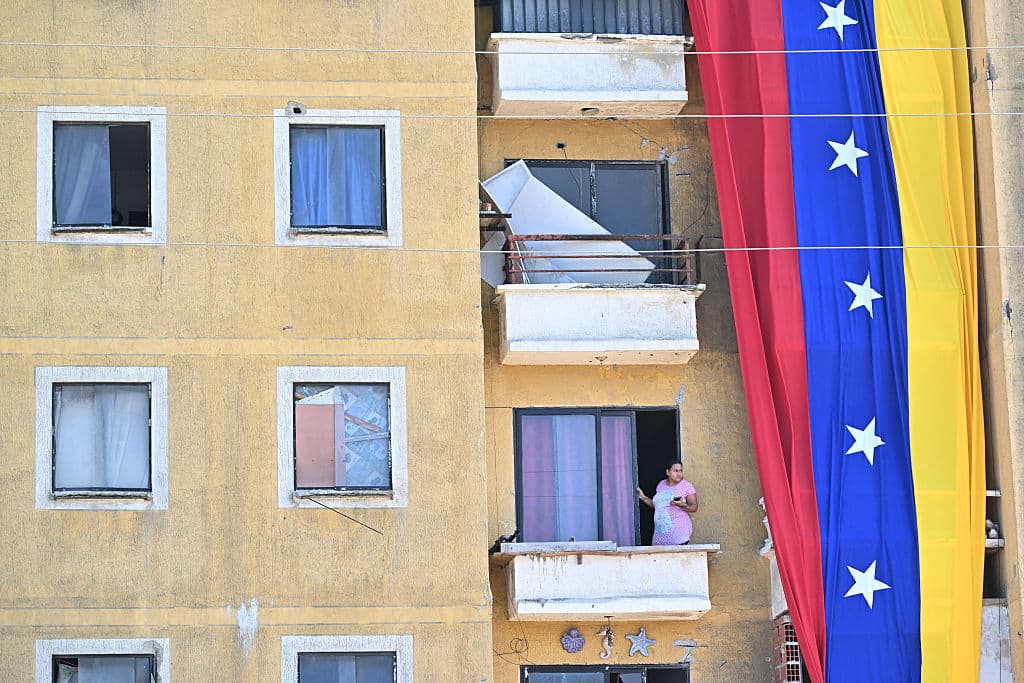 <em>Una mujer embarazada mira desde el balcón de un edificio que exhibe la bandera nacional de Venezuela en Catia La Mar, Venezuela, el 28 de julio de 2026, un mes después de que un terremoto azotara la zona. Recuperarse de los terremotos en Venezuela llevará años, dijo la Cruz Roja el 24 de julio, un mes después del desastre del 24 de junio que quitó la vida a más de 5000 personas. (Juan BARRETO/AFP vía Getty Images)</em>