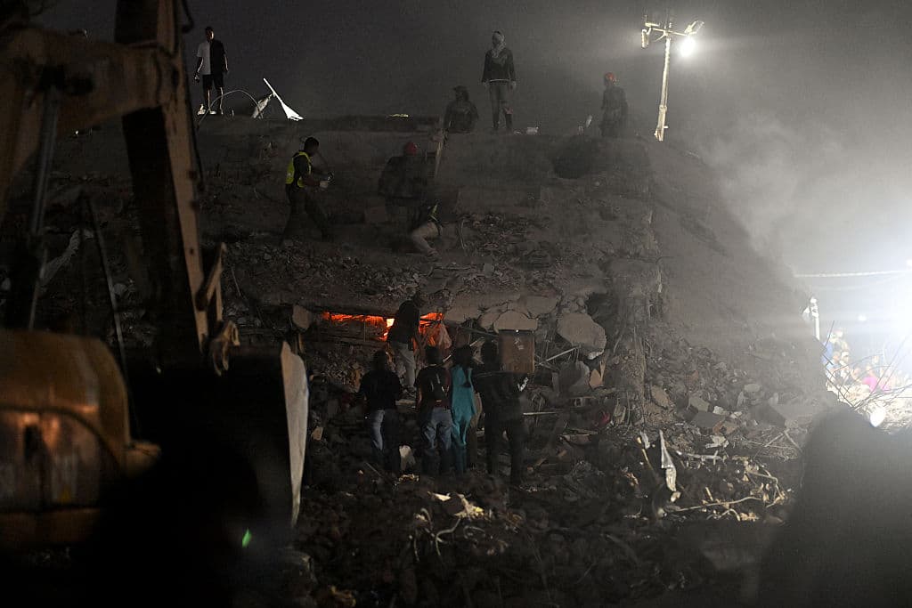 <em>Personas y equipos de rescate buscan cadáveres entre los escombros de edificios derrumbados en Caraballeda, Venezuela, el 30 de julio de 2026. El 30 de julio de 2026, las autoridades venezolanas comenzaron a demoler edificios en el estado de La Guaira, la región más afectada por los dos terremotos del mes pasado, observó AFP. (Juan BARRETO/AFP vía Getty Images)</em>