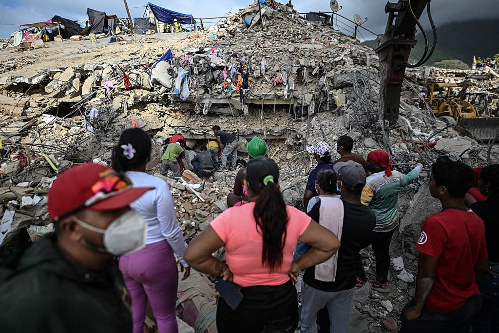 <em>La gente busca cuerpos entre los escombros de un edificio en Caraballeda, Venezuela, el 22 de julio de 2026, casi un mes después de los terremotos del 24 de junio. (Juan BARRETO/AFP vía Getty Images)</em>