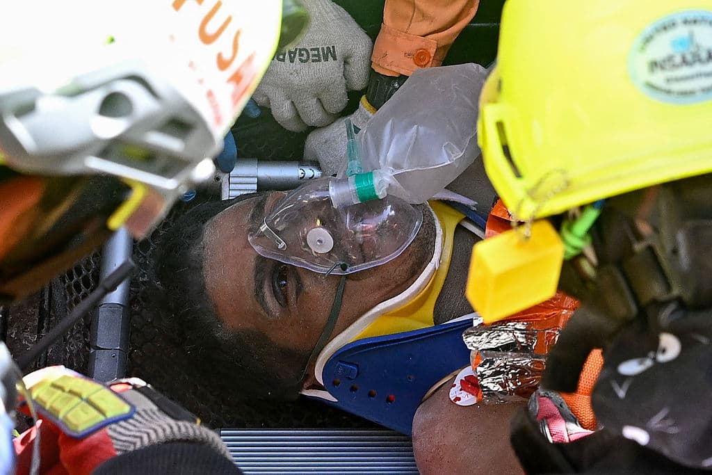<em>Hernán Gil, sobreviviente de los dos terremotos de Venezuela, recibe asistencia de miembros de equipos de rescate internacionales antes de ser trasladado de urgencia a una ambulancia en Catia La Mar, estado de La Guaira, Venezuela, el 2 de julio de 2026, ocho días después del terremoto. Hernán Gil, un guardia de seguridad de 43 años, había sido enterrado en la caseta del edificio de siete pisos donde trabajaba en Catia La Mar, una zona costera del estado de La Guaira devastada por el desastre. (Federico PARRA/AFP vía Getty Images)</em>