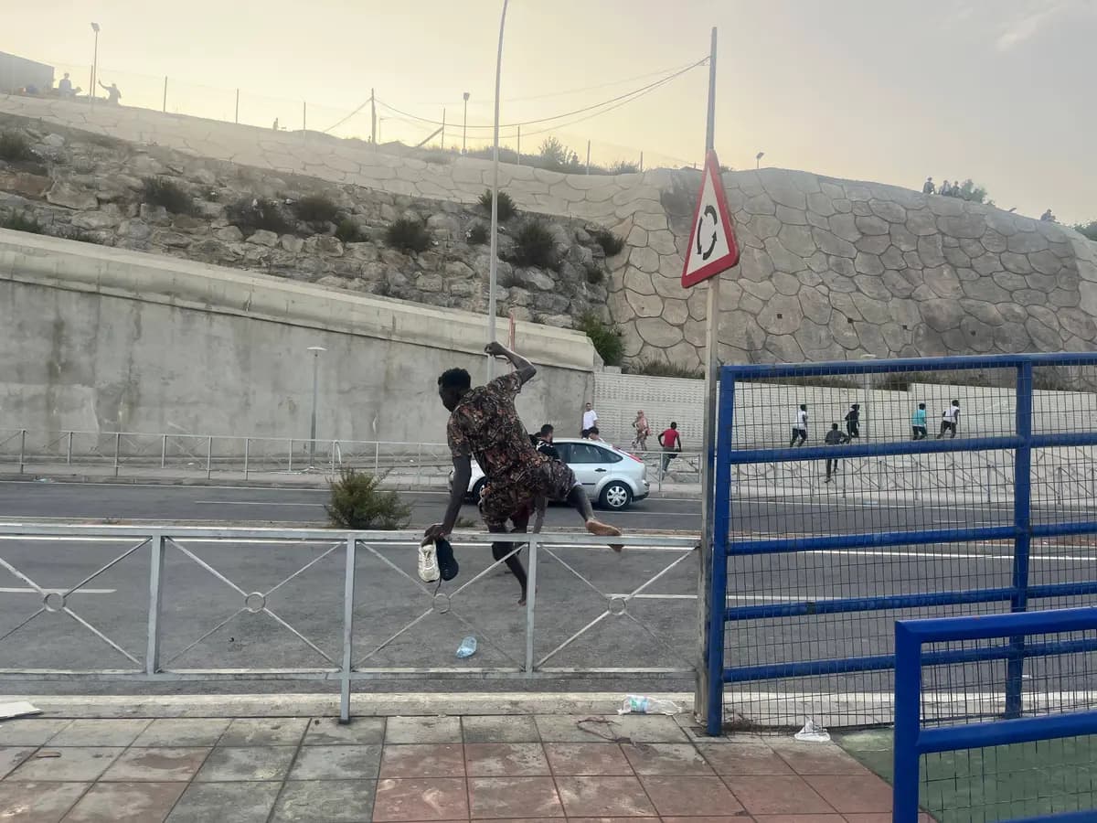 Un migrante africano trepa por una barrera al costado de la carretera mientras corre hacia la ciudad de Ceuta el 31 de julio de 2026. (Etienne Fauchaire/The Epoch Times)