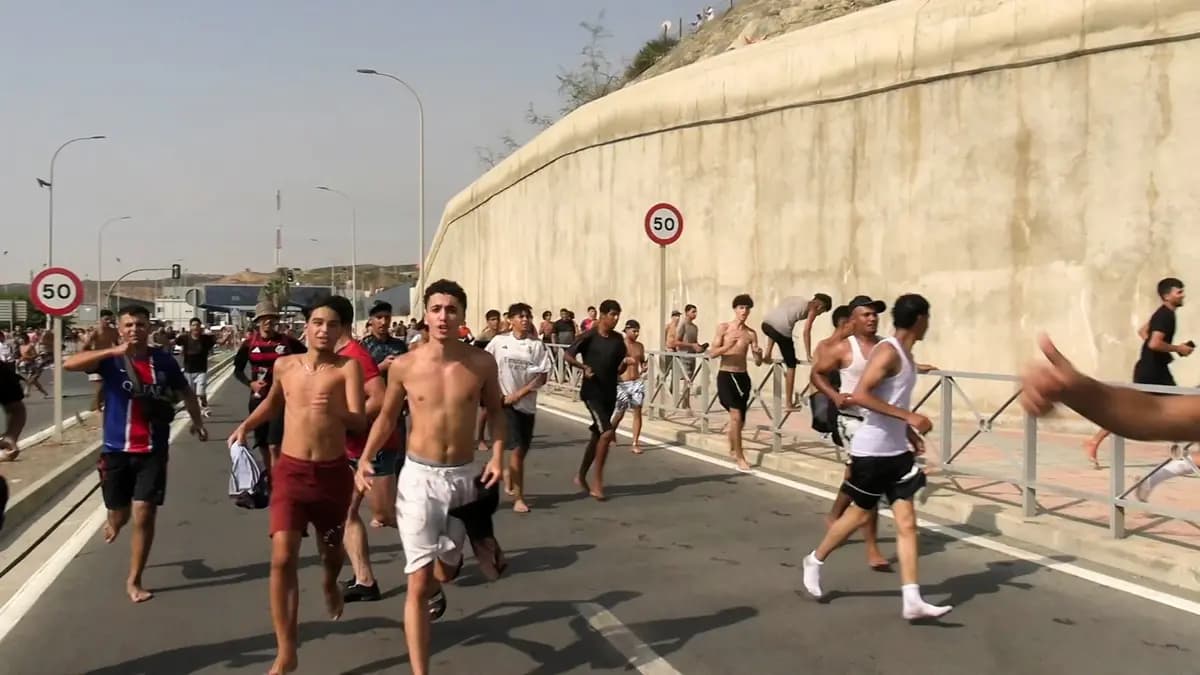 <em>Inmigrantes corren y vitorean mientras cruzan a pie desde Marruecos hacia la ciudad autónoma española de Ceuta, en el norte de África, tras nadar desde la costa marroquí y desbordar a la policía en el rompeolas de la ciudad, según la Guardia Civil española, en Ceuta, España, el 30 de julio de 2026. (Captura de pantalla obtenida de un vídeo distribuido. Faro TV vía Reuters).</em>