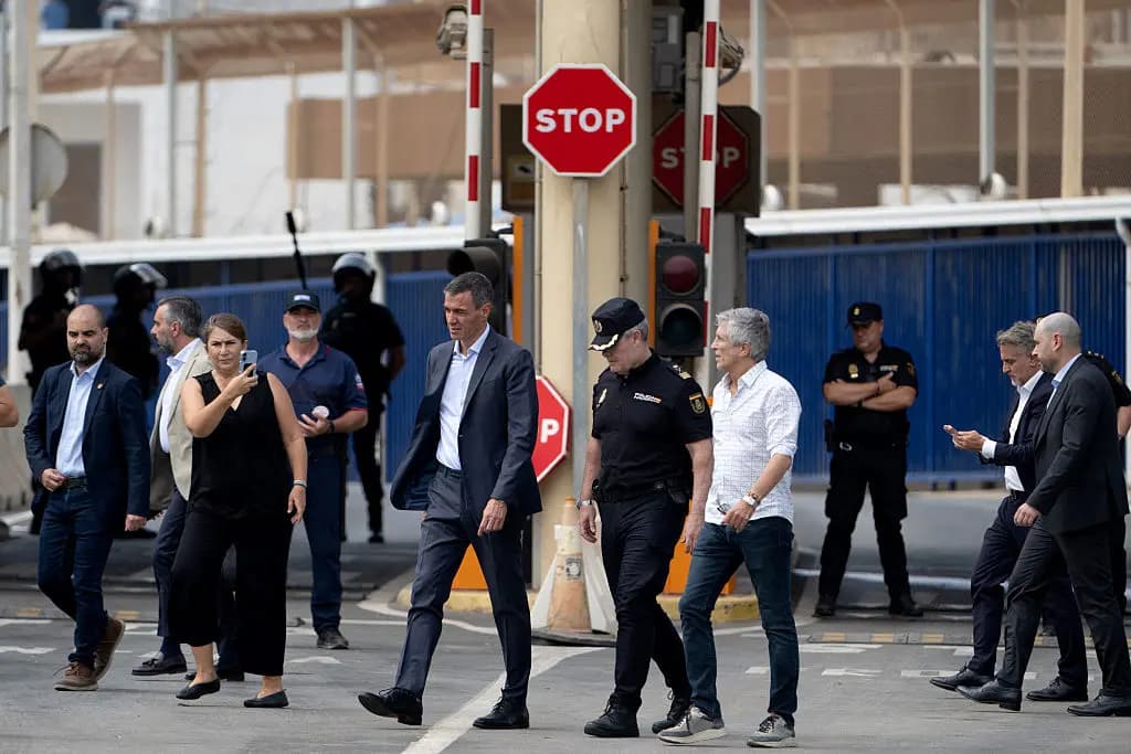 <em>El presidente del Gobierno español, Pedro Sánchez (C), y el ministro del Interior, Fernando Grande Marlaska, caminan junto a la valla fronteriza de Tarajal, que separa la ciudad autónoma española de Ceuta, en el norte de África, de Marruecos, durante una visita en medio de una de las mayores crisis migratorias en la frontera del país, cuando miles de migrantes cruzaron la frontera desde Marruecos durante la noche del 31 de julio de 2026. (Jorge Guerrero/AFP vía Getty Images).</em>