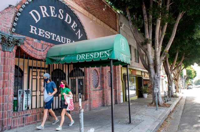 Varias personas pasan junto a un restaurante cerrado debido a las restricciones y confinamientos por la pandemia en Los Ángeles, el 8 de diciembre de 2020. (Valerie Macon/AFP vía Getty Images).