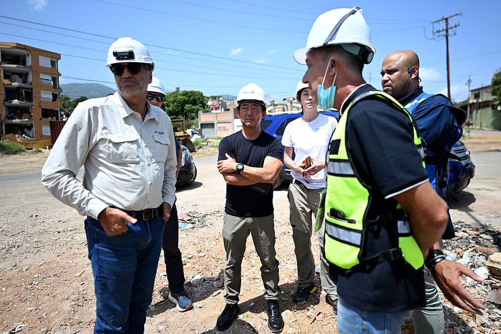 <em>El ingeniero estructural japonés-estadounidense Hideki "Kit" Miyamoto (C) ante edificios destruidos por los terremotos del 24 de junio en Catia La Mar, Venezuela, el 22 de julio de 2026. (Juan BARRETO / AFP vía Getty Images)</em>