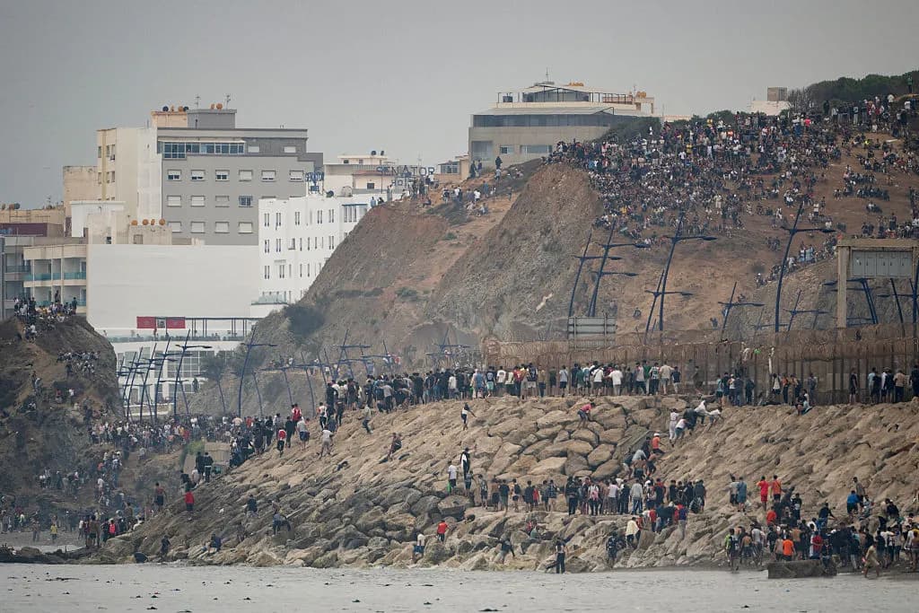Migrantes regresan a Marruecos después de haber cruzado la frontera para entrar en el enclave español de Ceuta, en el norte de África, el 31 de julio de 2026. Miles de personas atravesaron durante la noche desde Marruecos, mientras el presidente del Gobierno español se disponía a llegar a la ciudad para gestionar la crisis fronteriza. En los días previos, más de 50,000 migrantes habían entrado en el territorio, cuya población ronda los 80,000 habitantes. (Jorge Guerrero/AFP vía Getty Images)