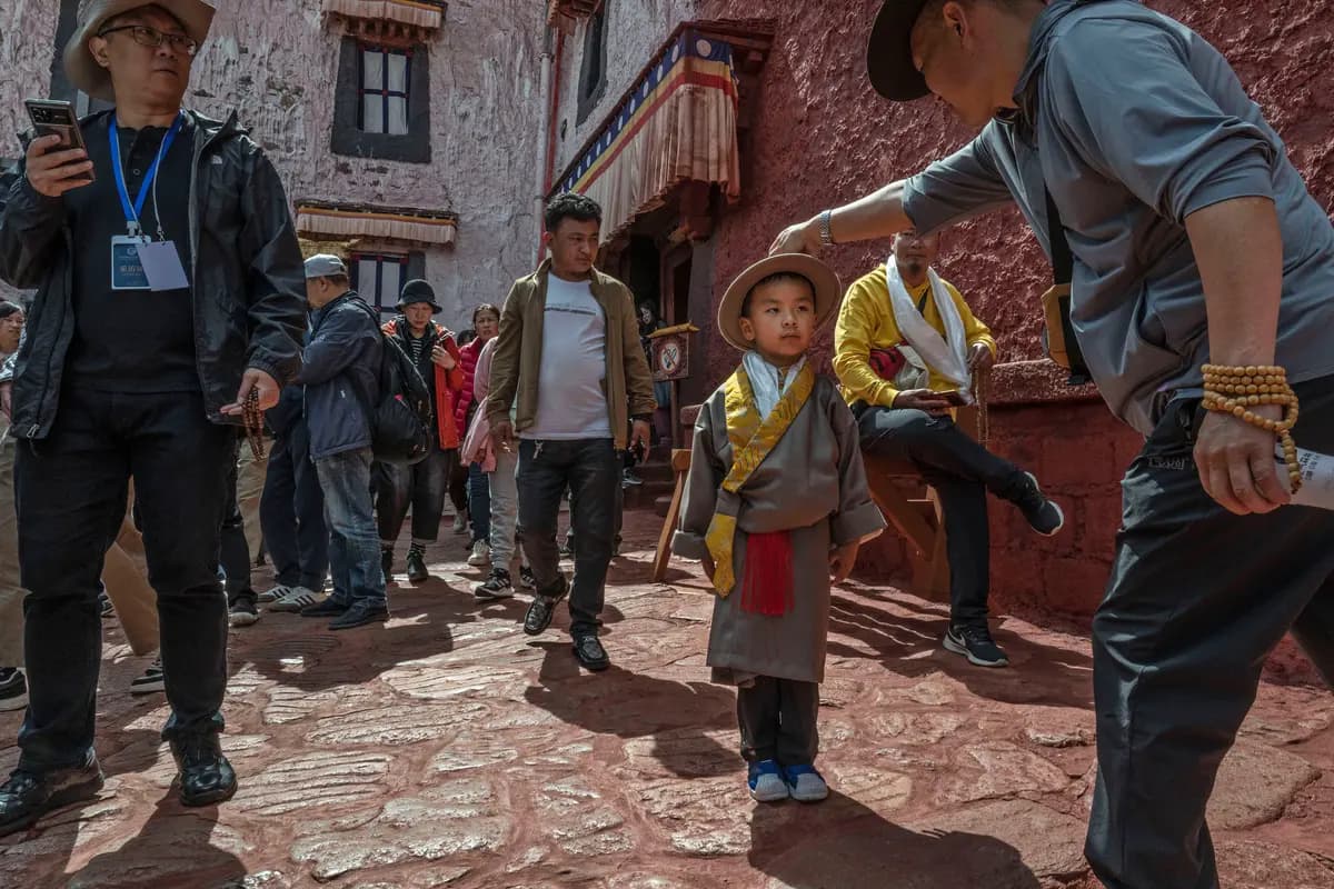 Un hombre budista tibetano le ajusta el sombrero a un niño vestido con ropa tradicional durante una visita al Palacio del Potala, sitio declarado Patrimonio Mundial por la UNESCO, en el marco de una visita organizada por el Estado en Lhasa, Tíbet, China, el 16 de junio de 2023. (Kevin Frayer/Getty Images)