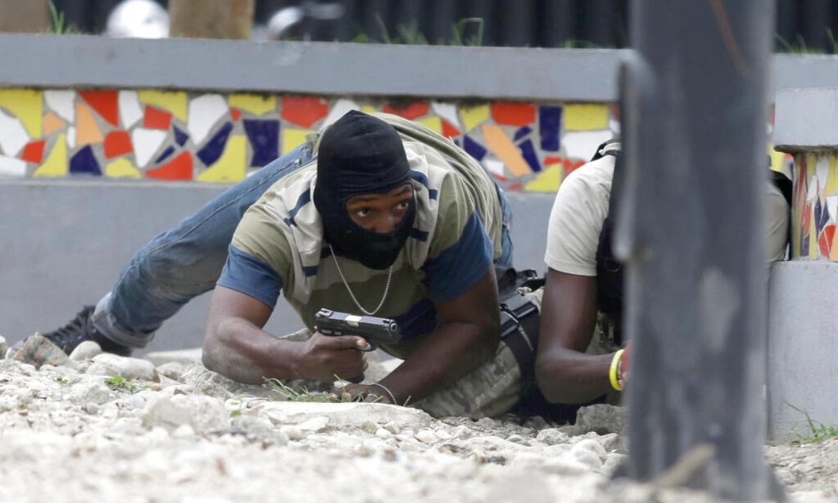 Agentes de policía armados fuera de servicio se ponen a cubierto durante un intercambio de disparos con soldados del ejército mientras protestan por el salario y las condiciones laborales de la policía en Puerto Príncipe, Haití, el 23 de febrero de 2020. (Dieu Nalio Chery/Foto AP)