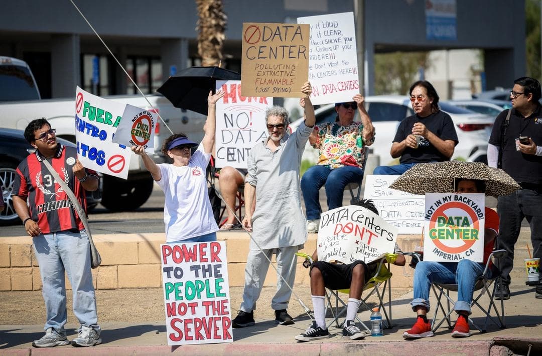 Manifestantes ondean pancartas durante una protesta a nivel nacional contra la expansión de los centros de datos de inteligencia artificial, en Imperial, California, el 18 de julio de 2026. Algunas de las voces de la oposición señalaron que su principal problema es la falta de transparencia por parte del gobierno. (Sandy Huffak/AFP vía Getty Images)