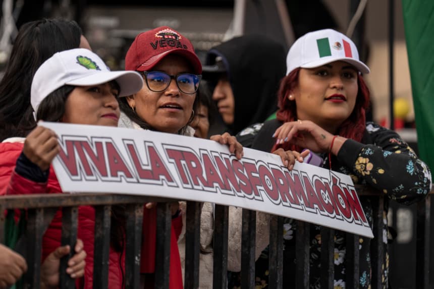 Personas asisten con pancartas al evento para conmemorar el séptimo año del partido MORENA y su movimiento "4T" gobernando el país en el Zócalo el 6 de diciembre de 2025 en la Ciudad de México. (Cristopher Rogel Blanquet/Getty Images)