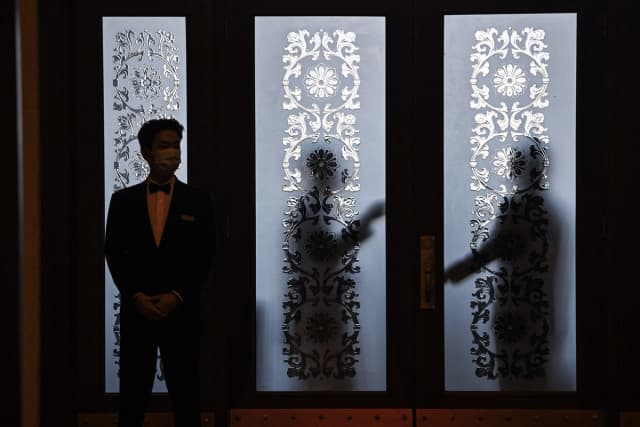 Guardias de seguridad se encuentran detrás de una puerta de cristal en el Gran Salón del Pueblo durante la XIV Asamblea Popular Nacional (APN) en Beijing, el 6 de marzo de 2024. (Foto de Greg Baker/AFP vía Getty Images).