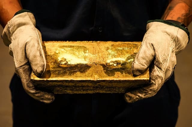 Un refinador sostiene un lingote de oro tras haberlo extraído de un molde en la fundición, el 29 de abril de 2025. Imagen ilustrativa (DAVID GRAY/AFP vía Getty Images)