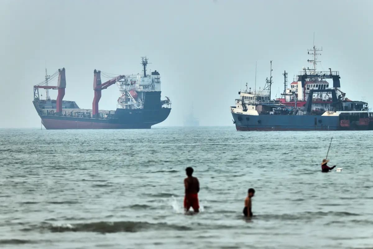 <em>Varias personas caminan por el agua con buques de carga anclados al fondo, en el estrecho de Ormuz, frente a Bandar Abbas, Irán, el 30 de junio de 2026. (Amirhosein Khorgooi/ISNA vía AP).</em>