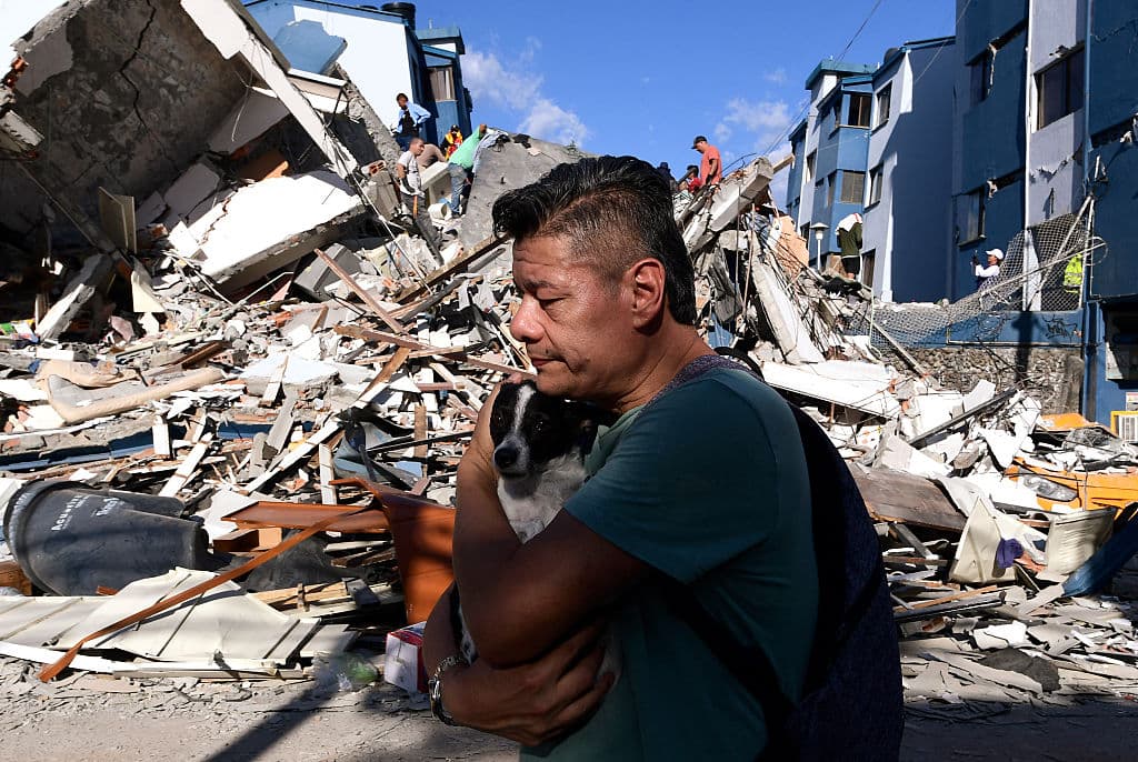 Un hombre lleva un perro mientras camina entre los escombros de un edificio derrumbado tras el terremoto en Pereira, Colombia, el 10 de agosto de 2026. Un potente sismo sacudió Colombia y países latinoamericanos vecinos el 10 de agosto de 2026, (Foto de Jaime SALDARRIAGA / AFP vía Getty Images)