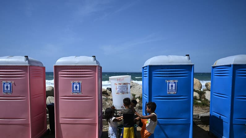 <em>Niños desplazados después de los dos terremotos que azotaron la región se lavan las manos en la 'Ciudad Carpita', un refugio improvisado en Mare Abajo, en La Guaira, Venezuela, el 14 de julio de 2026.  (Raúl ARBOLEDA/AFP vía Getty Images)</em>