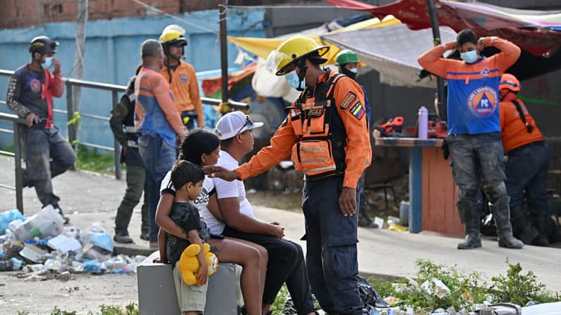 <em>Personal de un equipo de rescate consuela a una mujer con un niño en Punta Tanaguarenas, Venezuela, el 23 de julio de 2026, casi un mes después de los terremotos del 24 de junio. (Juan BARRETO/AFP vía Getty Images)</em>